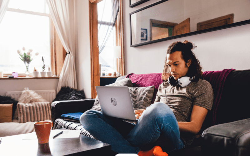 Jong volwassen man achter laptop op de grond in huiskamer